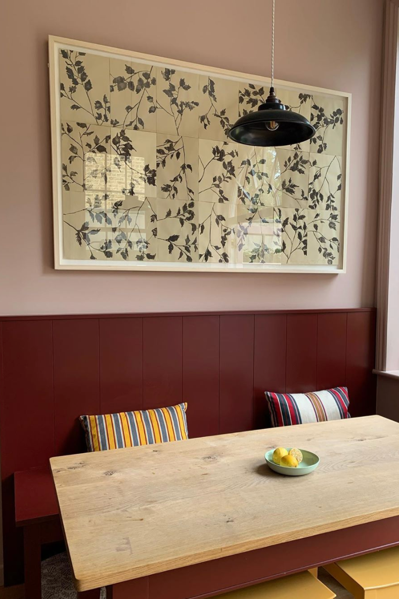 Dining area with a wooden table, colorful chairs, and floral artwork on the wall.
